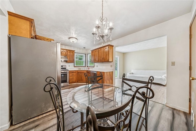 dining space with light wood-style floors, a chandelier, and baseboards