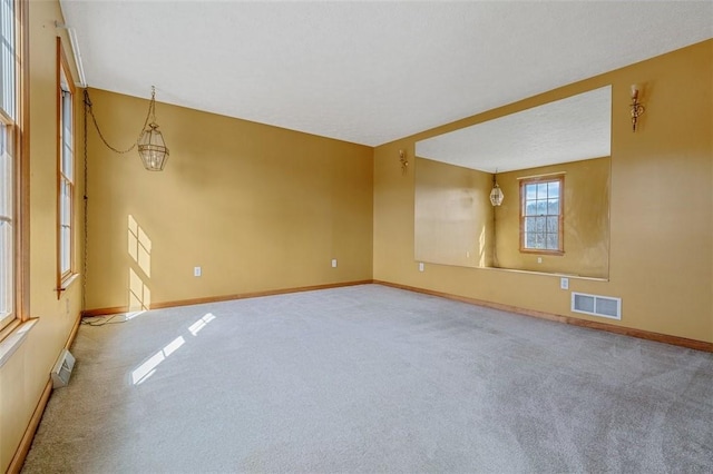 unfurnished room featuring carpet, visible vents, and baseboards
