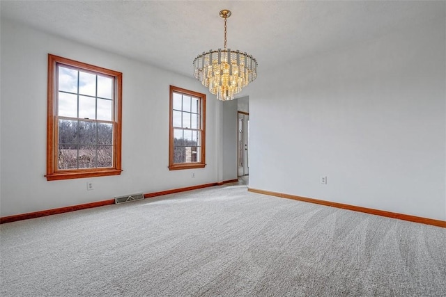 empty room featuring a notable chandelier, carpet floors, and baseboards