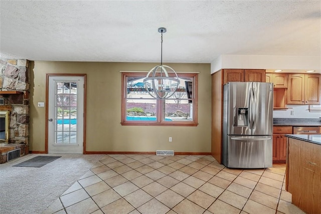 kitchen with a textured ceiling, visible vents, decorative light fixtures, a notable chandelier, and stainless steel fridge with ice dispenser