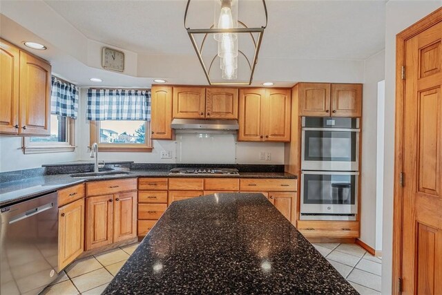 kitchen featuring dark stone counters, a sink, stainless steel appliances, and under cabinet range hood