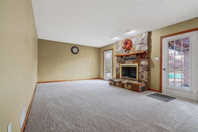 unfurnished living room with a textured ceiling, visible vents, carpet floors, and a fireplace
