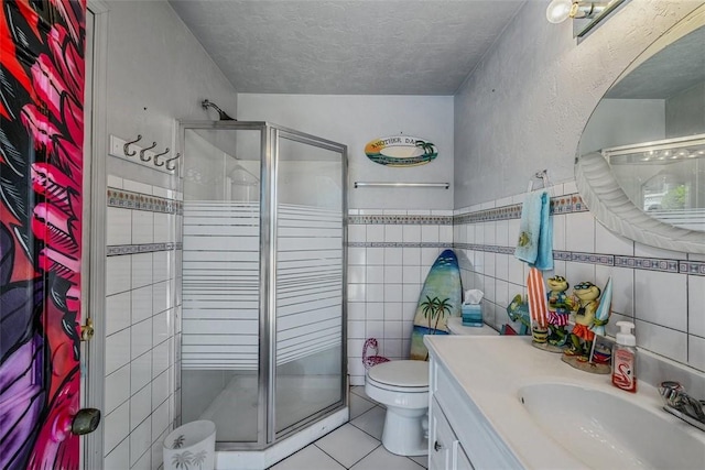 bathroom featuring tile patterned floors, toilet, vanity, a stall shower, and a textured ceiling