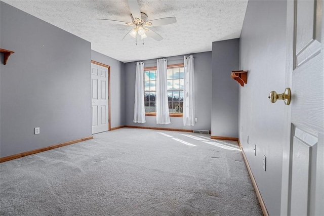 carpeted empty room with a textured ceiling, visible vents, a ceiling fan, and baseboards