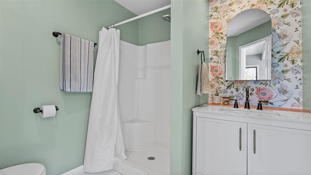 bathroom with a shower stall, wallpapered walls, baseboards, toilet, and vanity