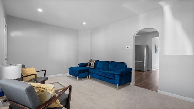 carpeted living room featuring recessed lighting, arched walkways, and baseboards