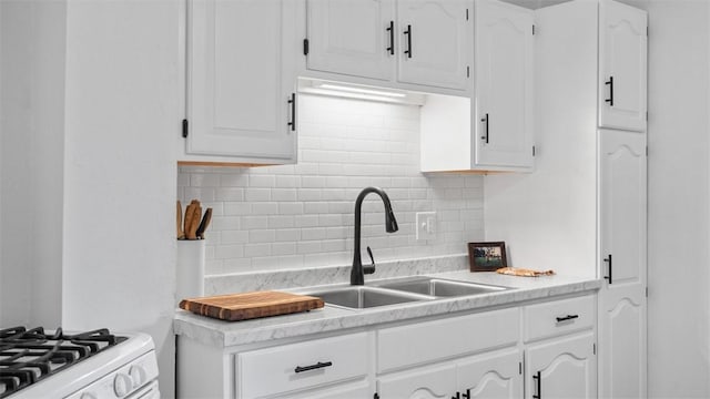 kitchen featuring white cabinetry, tasteful backsplash, light countertops, and a sink