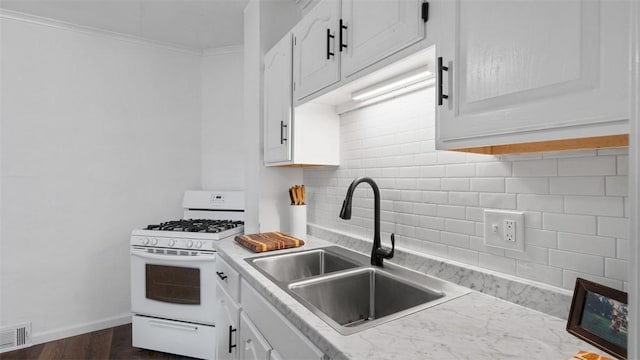kitchen with a sink, white gas stove, visible vents, white cabinetry, and backsplash