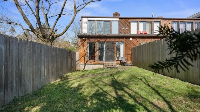 back of house featuring a lawn, a chimney, and fence