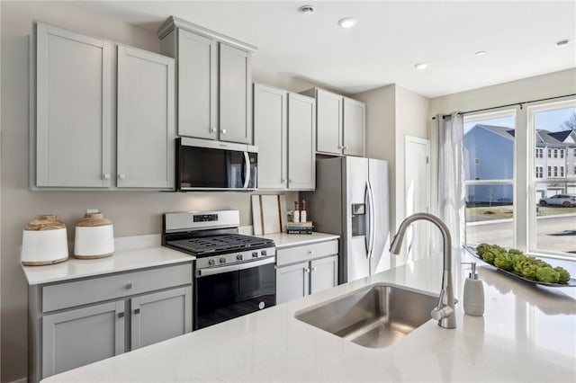 kitchen with light countertops, a sink, stainless steel appliances, and gray cabinets
