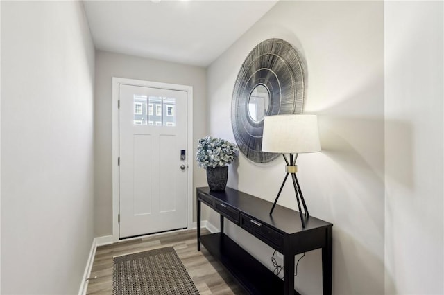 doorway featuring light wood-style flooring and baseboards
