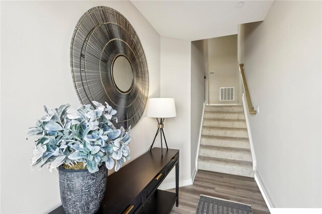 staircase featuring baseboards, visible vents, and wood finished floors