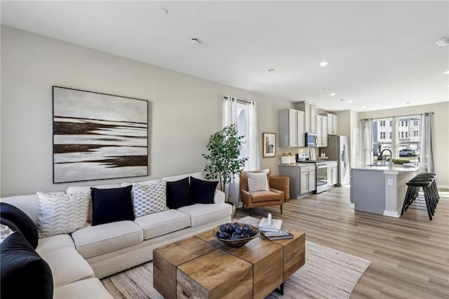living area featuring baseboards, light wood-type flooring, and recessed lighting