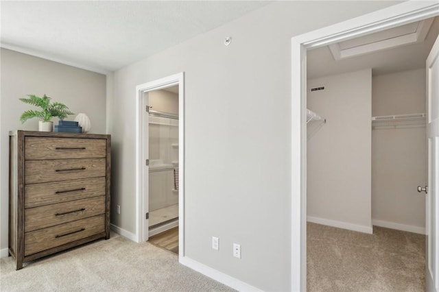unfurnished bedroom with baseboards, light carpet, a walk in closet, and a closet