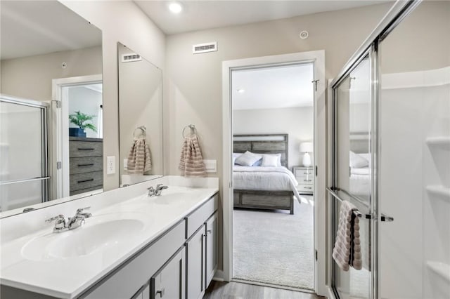 ensuite bathroom with double vanity, a shower stall, ensuite bath, and a sink