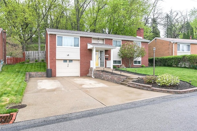 split foyer home featuring concrete driveway, an attached garage, fence, brick siding, and a front lawn