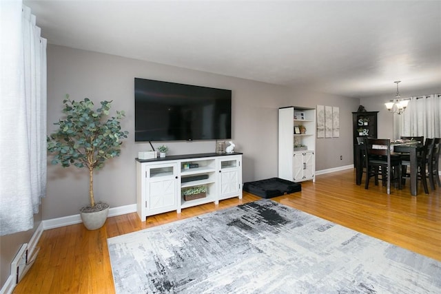 living area featuring an inviting chandelier, wood finished floors, visible vents, and baseboards