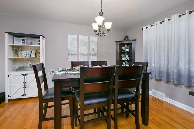 dining space with baseboards, visible vents, a notable chandelier, and light wood finished floors
