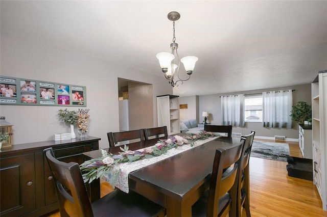 dining area featuring light wood-style floors and a notable chandelier