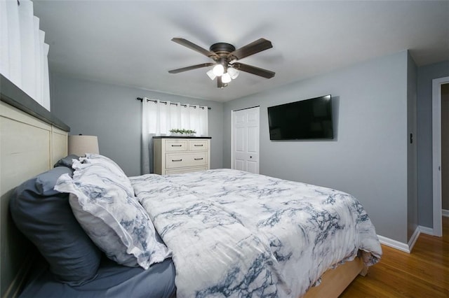 bedroom featuring baseboards, wood finished floors, ceiling fan, and a closet