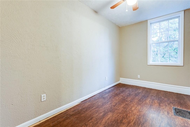 unfurnished room with ceiling fan, visible vents, baseboards, vaulted ceiling, and dark wood-type flooring