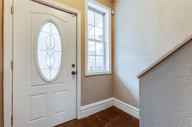 entrance foyer with baseboards, dark wood-type flooring, a textured wall, and plenty of natural light
