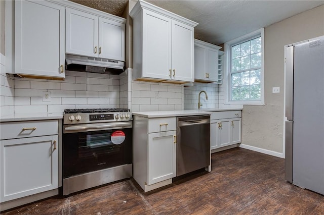 kitchen with decorative backsplash, appliances with stainless steel finishes, light countertops, baseboards, and under cabinet range hood