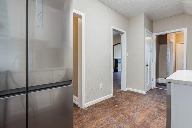 interior space featuring a textured ceiling, dark wood-style floors, and baseboards