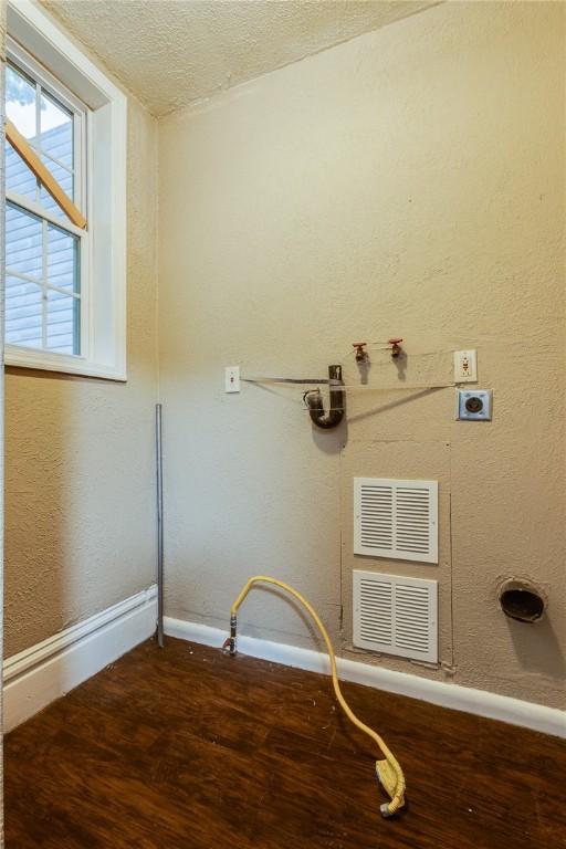clothes washing area featuring laundry area, visible vents, baseboards, a textured ceiling, and wood finished floors