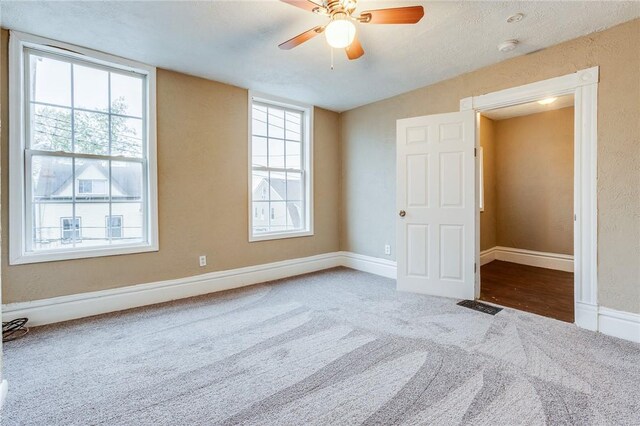 unfurnished bedroom with a ceiling fan, carpet flooring, baseboards, and visible vents