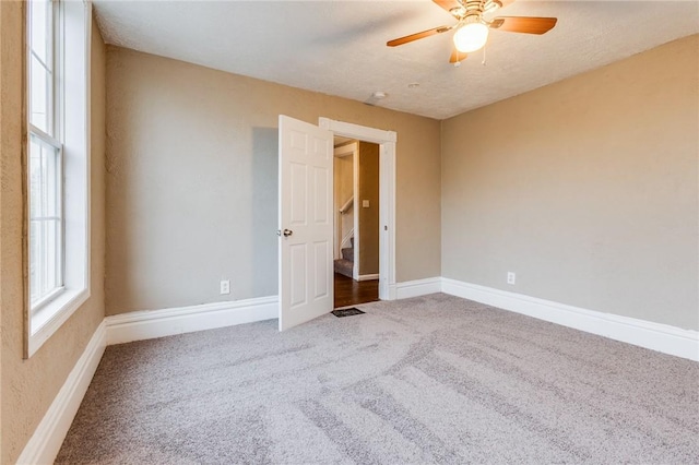 spare room with baseboards, ceiling fan, and carpet