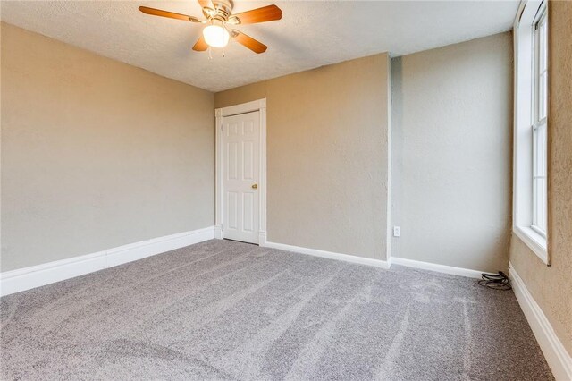 carpeted empty room featuring a textured ceiling, a ceiling fan, and baseboards