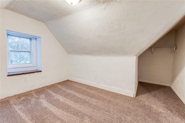 bonus room with a textured ceiling, baseboards, vaulted ceiling, and carpet floors