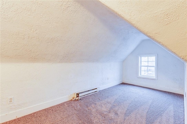 additional living space with a baseboard radiator, vaulted ceiling, carpet flooring, baseboards, and a textured ceiling