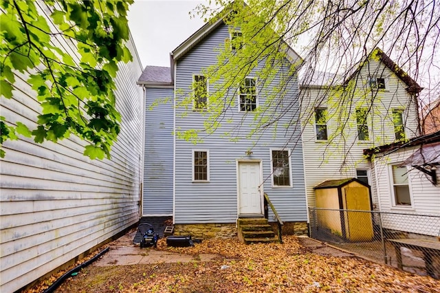 rear view of property with an outbuilding, a storage unit, and entry steps