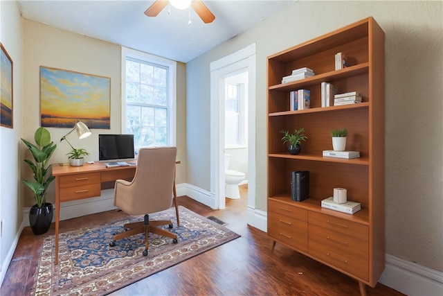 office featuring a ceiling fan, dark wood-style flooring, visible vents, and baseboards