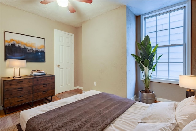 bedroom featuring baseboards, wood finished floors, a ceiling fan, and a textured wall