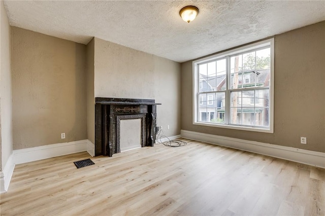 1226 Woodland Ave, Marshall Shadeland, PA 15212 - unfurnished living room with a textured ceiling, wood finished floors, a fireplace, baseboards, and a textured wall
