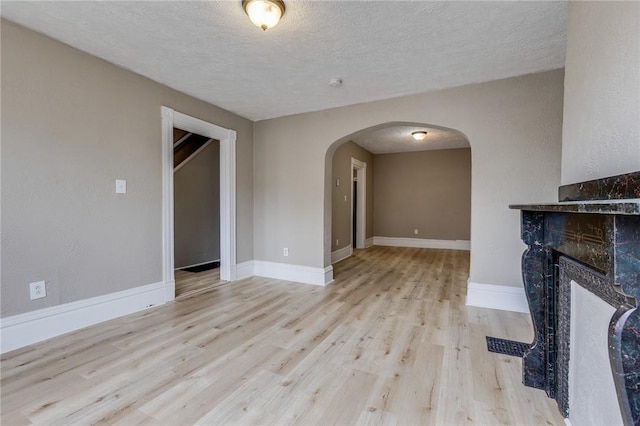 1226 Woodland Ave, Marshall Shadeland, PA 15212 - unfurnished living room with arched walkways, wood finished floors, a textured ceiling, a fireplace, and baseboards