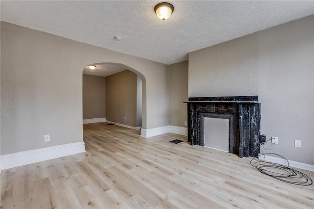 1226 Woodland Ave, Marshall Shadeland, PA 15212 - unfurnished living room with arched walkways, wood finished floors, a textured ceiling, a premium fireplace, and baseboards