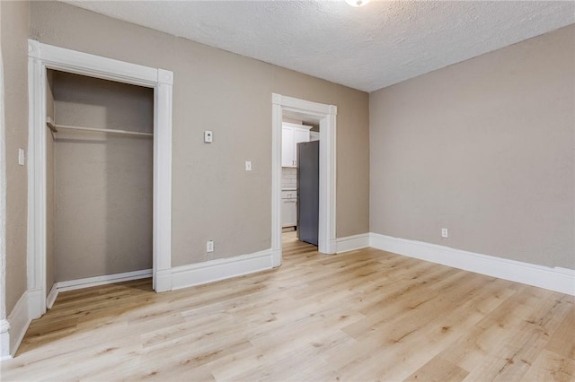 1226 Woodland Ave, Marshall Shadeland, PA 15212 - unfurnished bedroom featuring freestanding refrigerator, light wood-style flooring, a textured ceiling, baseboards, and a closet
