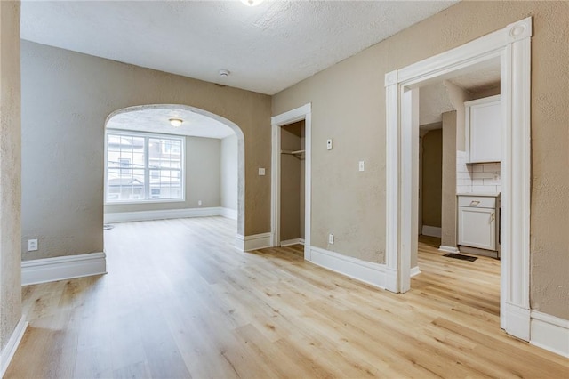 1226 Woodland Ave, Marshall Shadeland, PA 15212 - unfurnished room featuring arched walkways, light wood finished floors, a textured wall, and baseboards