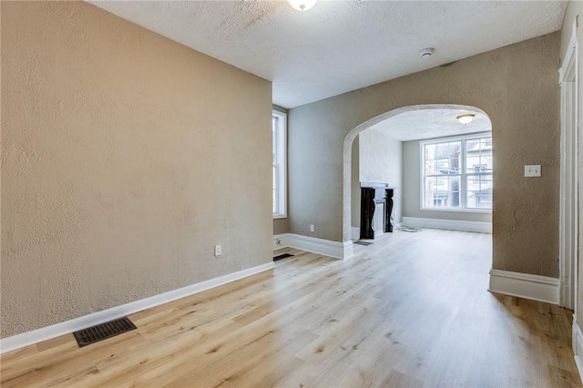 1226 Woodland Ave, Marshall Shadeland, PA 15212 - unfurnished living room with arched walkways, a textured wall, wood finished floors, baseboards, and a fireplace