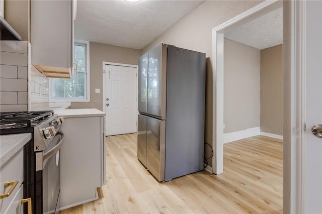 1226 Woodland Ave, Marshall Shadeland, PA 15212 - kitchen with appliances with stainless steel finishes, light wood-style floors, light countertops, exhaust hood, and a textured ceiling