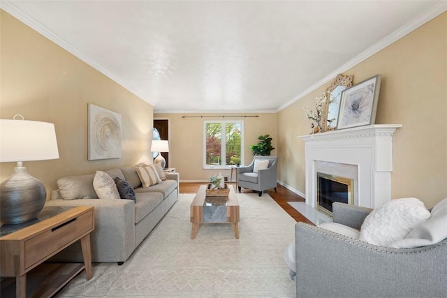 living area featuring ornamental molding, baseboards, light wood-style flooring, and a fireplace