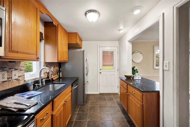 kitchen featuring a sink, stainless steel appliances, brown cabinetry, tasteful backsplash, and baseboards