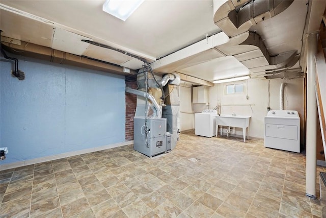 below grade area featuring stone finish floor, washer and dryer, heating unit, and a sink