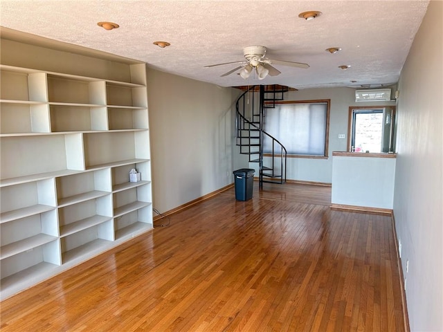 unfurnished living room with a textured ceiling, stairway, ceiling fan, baseboards, and wood-type flooring