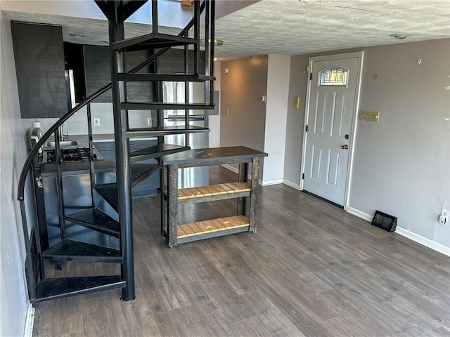 stairway with baseboards, wood finished floors, and a textured ceiling