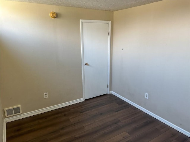 empty room featuring baseboards, visible vents, a textured ceiling, and dark wood-style flooring